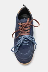 Championes de gamuza color marrón con detalles en cuero liso del mismo tono. Presentan cordones bicolores en naranja y negro, suela de goma plana y un detalle en color rojo en la parte trasera del talón.