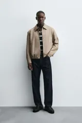 Cazadora regular fit color beige, confeccionada en tejido de algodón. Cuenta con cuello solapa, manga larga con puño elástico y trabilla, bolsillos de vivo en la cadera, bajo elástico y cierre frontal con cremallera.