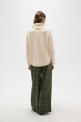 Polera de tejido de punto con cuello alto, diseño holgado y mangas largas. Presenta una textura de relieve tipo waffle en color natural.