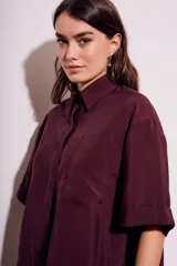 Camisa oversize color borgoña de mangas cortas con puños doblados y bolsillo en el pecho.