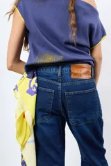 Jean de denim azul de tiro medio, con calce relajado, efecto balloon y costuras frontales. Cuenta con bolsillos traseros y etiqueta de cuero sintético con marca grabada en la parte posterior.
