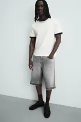 Bermuda de denim de algodón, color negro lavado, de corte ancho (baggy fit) y tiro medio. Presenta cinco bolsillos y bajo con acabado irregular deshilachado.