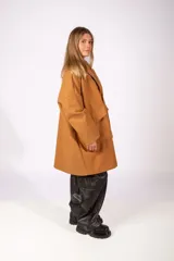 Tapado de paño color beige, de corte oversize, con solapas clásicas, cierre frontal con botones y bolsillos laterales amplios.