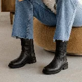 Bota de caña media en cuero negro con textura granulada, diseño de puntera reforzada y suela plana de goma con pequeño tacón.