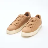 Zapatillas bajas de estilo urbano en color marrón, con suela y detalle en el talón en color crema. Presentan cierre mediante cordones al tono y diseño minimalista.
