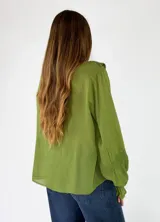 Blusa de algodón blanca con escote en V, mangas largas amplias y detalles de volados con encaje bordado en el frente.