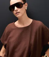 Blusa corta de estilo balonê confeccionada en tejido de viscosa, con mangas cortas amplias, escote redondo y ruedo fruncido que genera un efecto voluminoso.