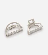Set de dos pinzas para el cabello confeccionadas en metal plateado, con diseño de media luna y estructura calada. Cuentan con un mecanismo de resorte resistente y dientes alineados para una sujeción firme.