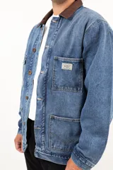 Campera de jean azul con cuello de corderito marrón, cierre con botones metálicos, cuatro bolsillos frontales y puños con botón.