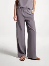 Pantalón de tiro medio color gris, de corte recto y holgado, con cintura elástica y aberturas laterales en el ruedo con detalle de franja en contraste.