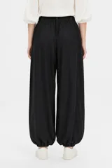 Pantalón de viscosa color negro, holgado de tiro alto, con bolsillos laterales, detalles de frunces en la cintura y botamangas elastizadas.