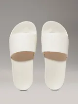 Ojotas Calvin Klein con tira ancha de tejido jacquard que presenta el logo de la marca en relieve. Poseen plantilla ergonómica moldeada con soporte para el arco y suela de EVA.