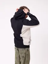 Canguro azul marino con capucha, bolsillo canguro frontal y paneles laterales en color bordó con ribetes blancos. Logo "Rusty" estampado en el pecho.