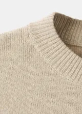 Jersey de punto de corte recto con diseño de rayas horizontales oscuras sobre fondo beige. Presenta cuello redondo, manga larga y tejido de punto medio.