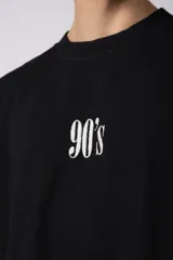 Remera negra de corte oversize con cuello redondo y estampa frontal pequeña con el texto 90's en color blanco.