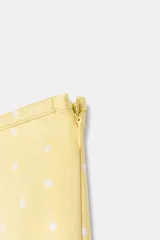 Shorts de tiro medio confeccionados en tejido satinado color amarillo con estampado de lunares blancos y bajo con vuelo.