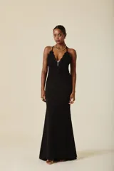 Vestido largo de fiesta color negro, con escote profundo en V y detalle de encaje bordado con pedrería en el torso. Presenta breteles finos cruzados en la espalda y falda de corte sirena con caída fluida.