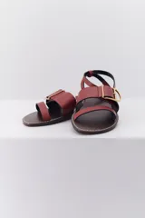 Sandalias planas con estampado animal, hebilla dorada y suela marrón.