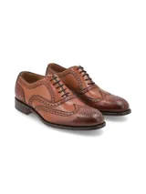 Zapato de vestir tipo Oxford con diseño brogue, confeccionado en cuero vacuno color cognac con acabado degradado en la puntera. Presenta cierre mediante cordones y suela de cuero con tacón bajo.