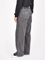 Pantalon de jean con efecto lavado, corte recto y holgado, con costuras verticales decorativas en el frente y bolsillos laterales.