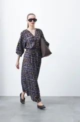 Vestido largo de silueta fluida con estampado abstracto en tonos azul, marrón y beige. Presenta escote en V con botones forrados y cintura elastizada. Mangas 3/4 abullonadas.
