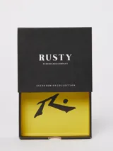 Billetera plegable Rusty con diseño bicolor, combinando una sección texturizada en color negro con una sección lisa en color gris. Incluye una placa metálica con el logo de la marca en la parte frontal.