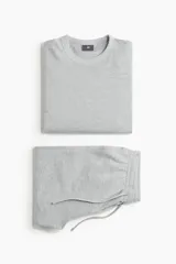 Conjunto de pijama de dos piezas en punto waffle gris claro, compuesto por una remera de manga larga con cuello redondo y un pantalón con cintura elástica y cordón de ajuste.