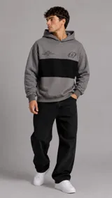 Hoodie de diseño color gris con una franja horizontal negra en el pecho, capucha y bolsillo tipo canguro. Presenta inscripciones y un logo estampado en la parte superior frontal.