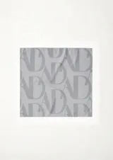 Pañuelo cuadrado de satén con estampado abstracto en tonos rojizos y grises, anudado en la parte inferior.