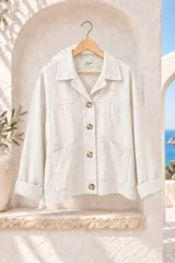 Chaqueta de gabardina elastizada color beige, con cuello camisero, cierre frontal de botones grandes carey y bolsillos delanteros aplicados. Cuenta con mangas largas con puños doblados y calce amplio.