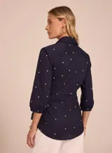 Blusa azul marino con estampado de lunares blancos, cuello camisero, mangas 3/4 y lazo en la cintura.