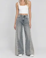 Pantalón jeans de tiro medio, corte wide leg y diseño amplio en las piernas. Presenta un estampado sutil en toda la prenda con franjas laterales de lavado más claro.