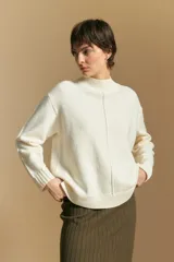 Polera de tejido de punto color blanco, con cuello alto acanalado, hombros caídos y detalle de costura vertical en el frente.