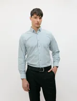 Camisa de manga larga de tejido Oxford color celeste, con cuello button-down, cierre frontal con botones al tono y un bolsillo aplicado en el pecho.