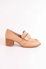 Mocasín color beige de cuero, con hebilla metálica plateada y taco de madera de 5 cm.