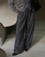 Pantalon de corte amplio y tiro alto con estampado de cuadros en tonos blanco y negro. Presenta cintura elástica con cordón ajustable y bolsillos laterales.
