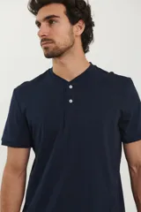 Remera tipo henley de manga corta, color beige, con cuello redondo y cartera de botones frontal.