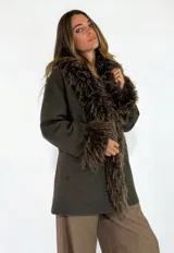 Chaqueta midi de paño color verde oliva, con cuello y puños de piel sintética de pelo largo en tono marrón. Presenta un diseño de corte recto y estructura clásica.