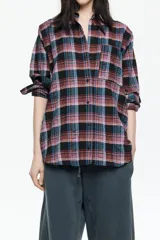 Camisa de corte recto y largo medio, confeccionada en tejido de algodón con textura. Presenta un diseño de cuadros en tonos rojo, negro y azul, cuello camisero, cierre frontal con botones, manga larga con puños abotonados y bolsillo de plastrón en el pecho.