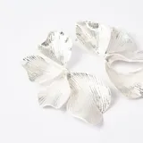 Aros tipo caravanas con diseño de pétalos de flor en color plateado, con textura estriada y acabado brillante.