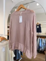 Sweater de punto calado color rosado, con diseño holgado, cuello redondo y mangas largas, que incluye una musculosa interior con terminación bordada en el bajo.