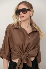 Camisa oversize de seda negra, con cuello camisero, cierre frontal con botones y mangas cortas con vuelta.