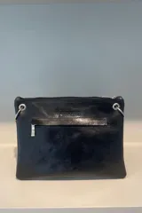 Sobre de cuero vacuno color bordó, con diseño frontal decorado con múltiples remaches metálicos circulares. Cuenta con correa larga ajustable y extraíble, cierre superior y bolsillo trasero con cierre.