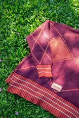 Saco tejido de punto con diseño de rombos en color bordó y naranja, con detalles en lurex. Presenta cuello redondo, cierre frontal con botones y mangas abullonadas con puños acanalados.