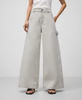 Pantalón palazzo de denim crudo para mujer, de tiro alto, con cierre de botón metálico, trabillas, bolsillos laterales y traseros, costura lateral desplazada al delantero de la pierna, pespuntes decorativos a contraste y parche logotipado en la espalda.