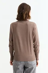 Sweater de punto fino en color verde menta, con cuello redondo, mangas largas y puños acanalados con detalle de botones metálicos laterales.