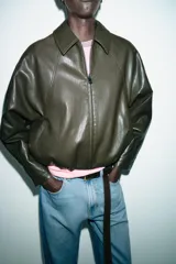Chaqueta estilo bomber de efecto piel en color verde oliva, con cuello solapa, cierre frontal con cremallera, mangas largas y bajo elástico.