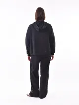 Campera deportiva negra con capucha, cierre frontal y apliques de lentejuelas en los hombros.