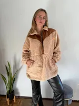 Canguro beige de corderito con detalles en cuero marrón en cuello, hombros y cierre.