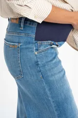 Jean de maternidad con corte wide leg y tiro medio, confeccionado en denim de algodón con acabado deshilachado en el ruedo.